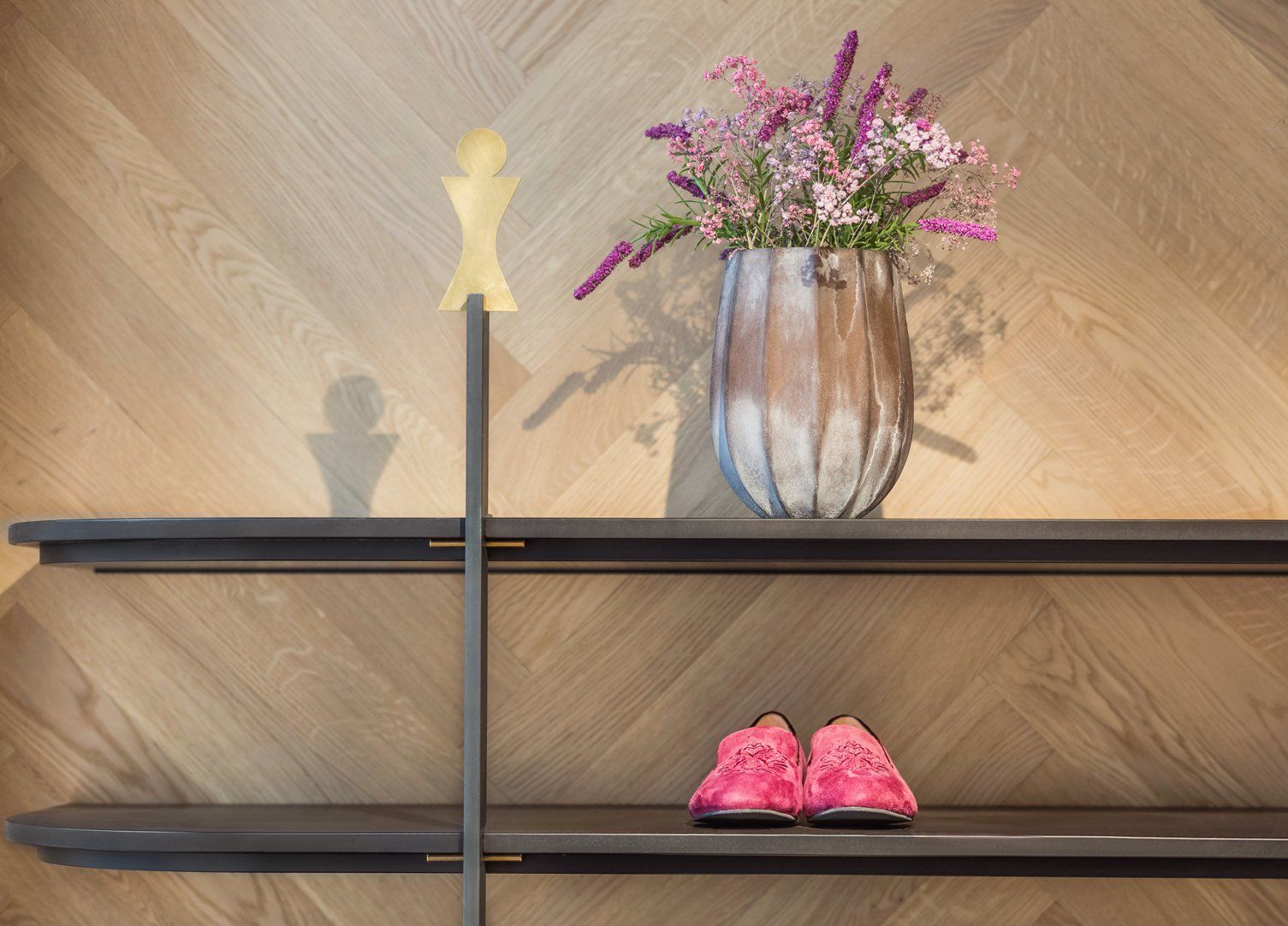 Eine Vase mit Blumen steht auf einem Regal neben einem Paar rosa Schuhe