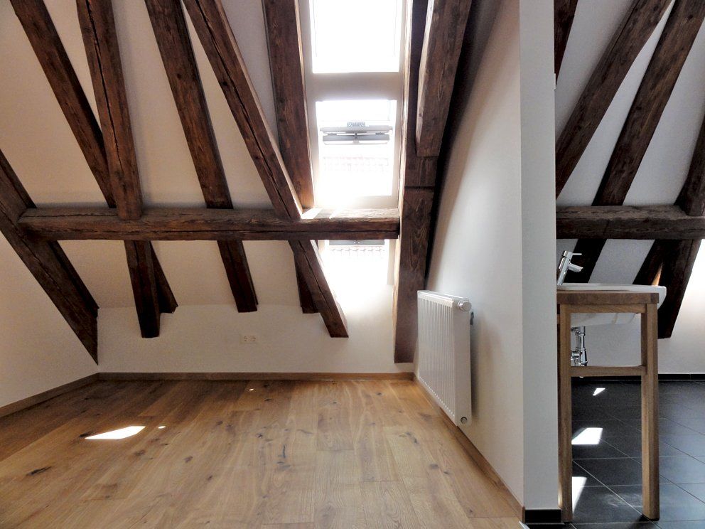 Ein leerer Raum mit Holzbalken und einem Fenster