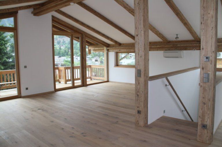 Ein leerer Raum mit Holzbalken und vielen Fenstern