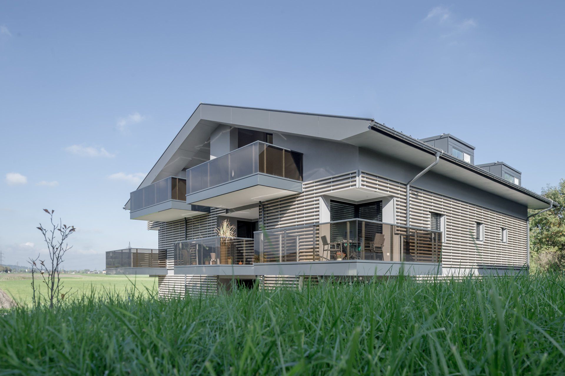 Ein Haus mit Balkon liegt mitten auf einer Wiese