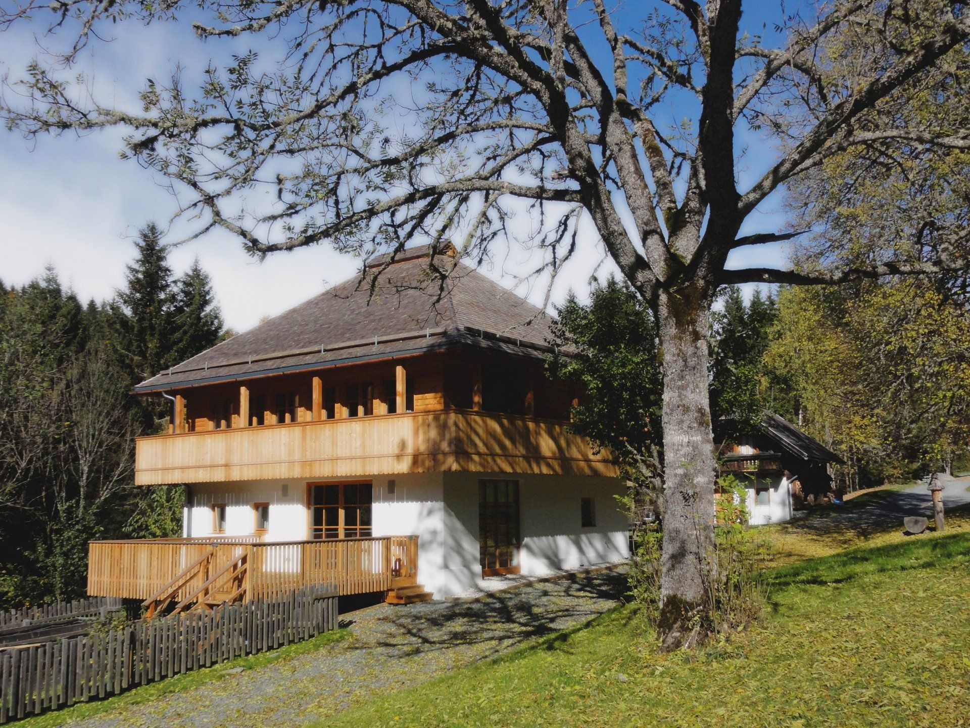 Ein Haus mit einer Holzterrasse ist von Bäumen umgeben