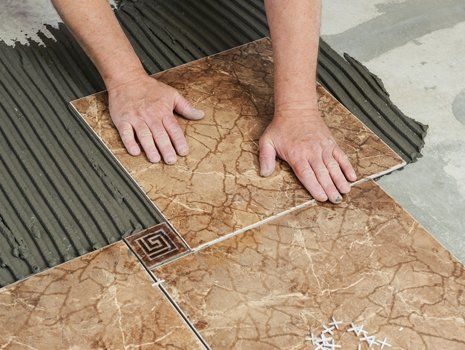 Flooring Installation — Man Placing Ceramic Floor Tile in Concord, NC Flooring Installation — Man Placing Ceramic Floor Tile in Concord, NC