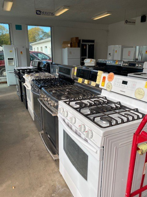 A row of stove tops and refrigerators in a store
