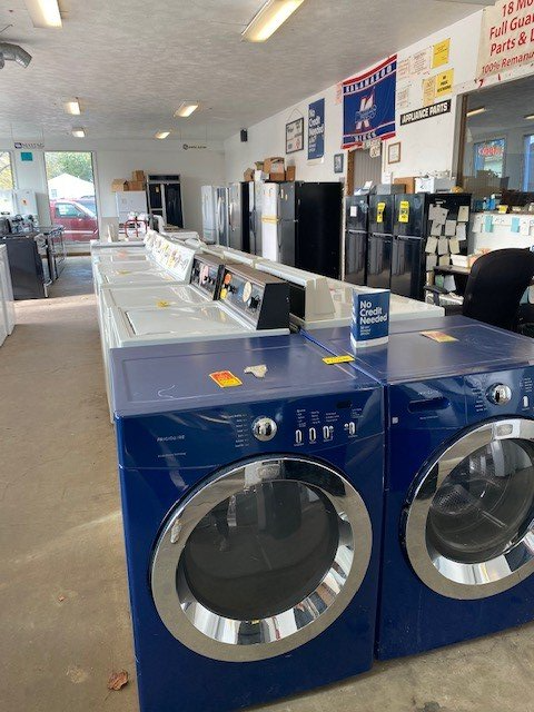 A row of blue washers and dryers in a laundromat
