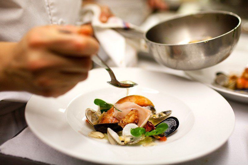 Une personne tient une cuillère au-dessus d'une assiette de nourriture.