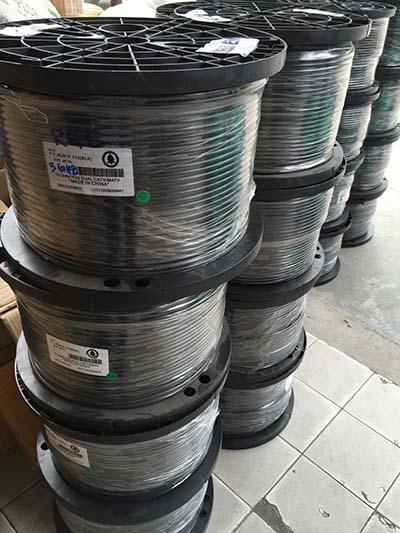 Spools of black wire stacked; some wrapped in plastic. Label visible on the front.