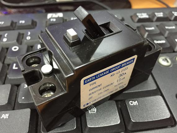 Earth leakage circuit breaker, black, on a keyboard. Labeled as 30A, type KP-LS 250.