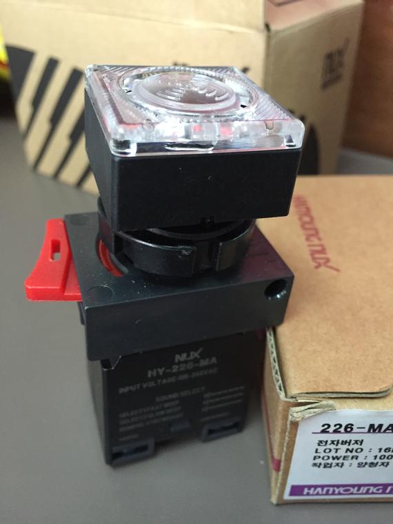 Black and red timer switch with a clear dial, on a table with a cardboard box nearby.