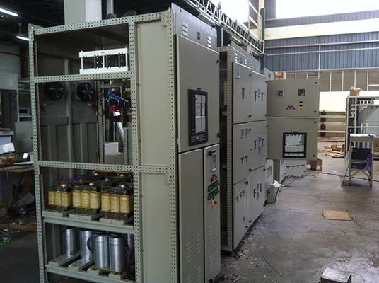 Electrical control panels in a factory setting, beige and gray, with various components and wiring.
