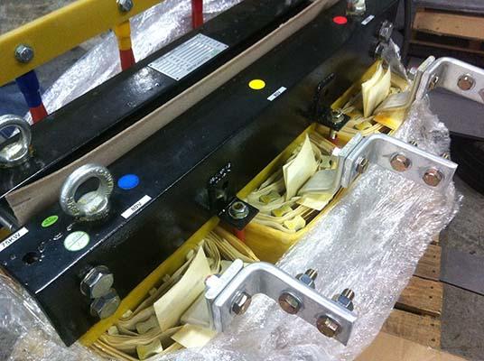 Black metal beam with colored dots and attached silver brackets, parts in a box.