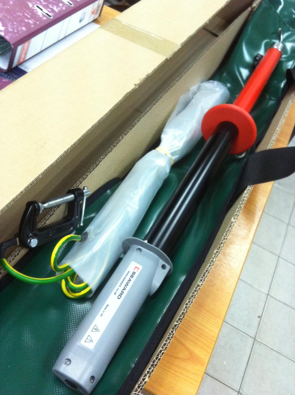 High-voltage grounding stick kit in a box. Black, red, and gray components with a grounding cable.