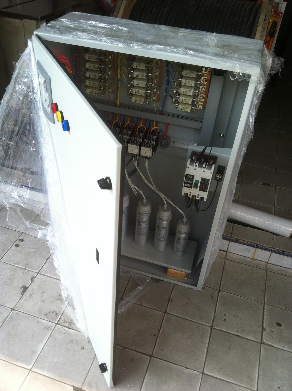 Electrical control panel with open door, showing capacitors and wiring.