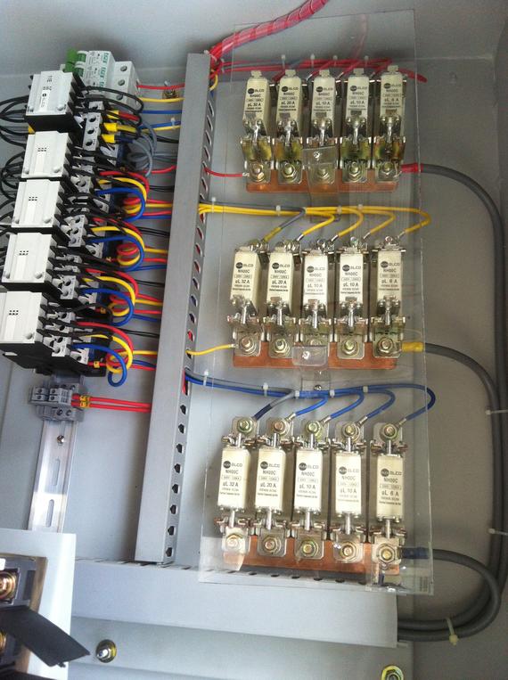 Electrical control panel with fuses and circuit breakers, connected by colored wires.