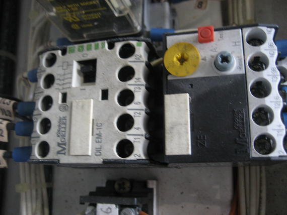 Two electrical relays attached to a panel. White and black units with screw terminals and labels.