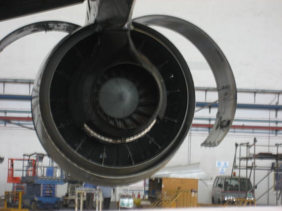 Close-up of an aircraft engine's intake in a maintenance hangar, showing internal components.