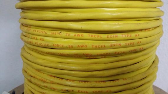 Yellow electrical cable wound on a spool, with orange text indicating specifications.