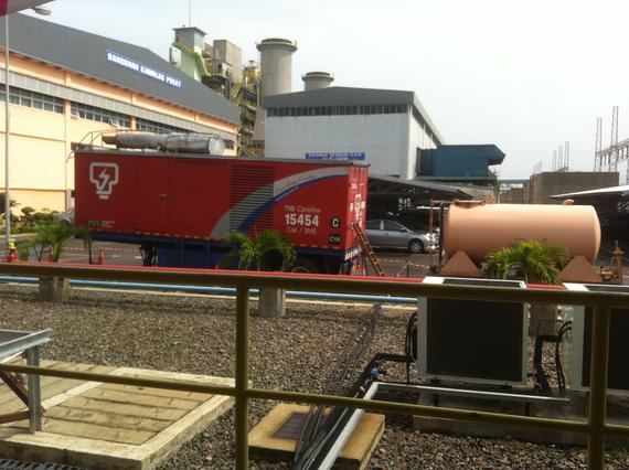 Red truck with logo parked near industrial buildings.