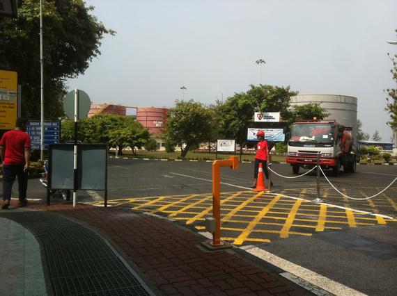 Two people in red near a fire truck and a traffic barrier in a paved area.