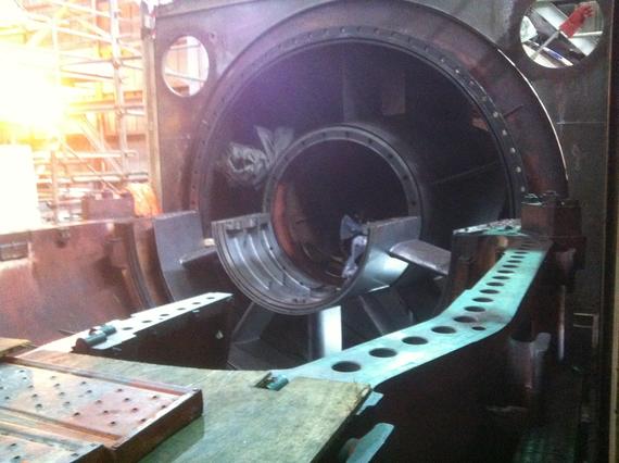 Large industrial lathe machine, showing an unfinished metal cylinder in the center.