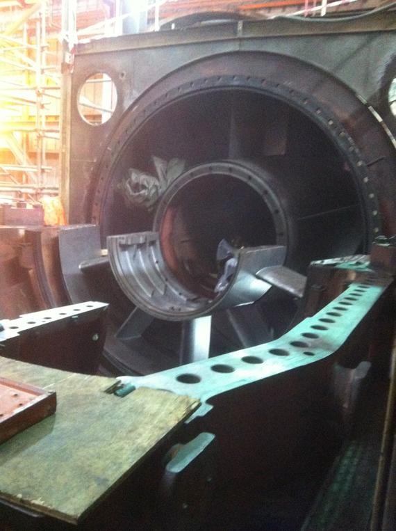 Inside of a large industrial machine, metal cylinder, dark interior, likely under repair.