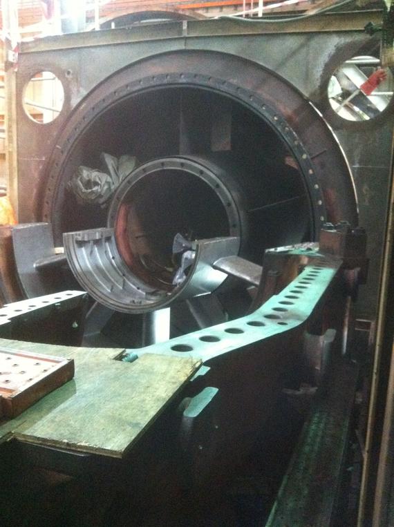 A large industrial machine with a cylindrical opening, holding a metal component.