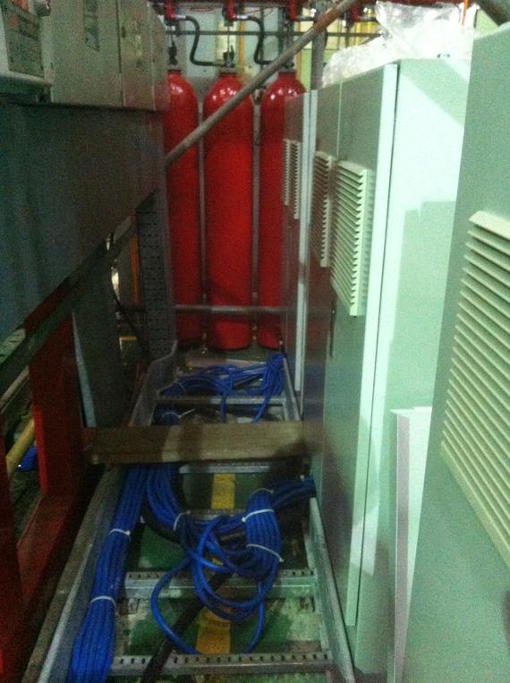 Red fire suppression cylinders, electrical wiring, and metal cabinets in an industrial setting.