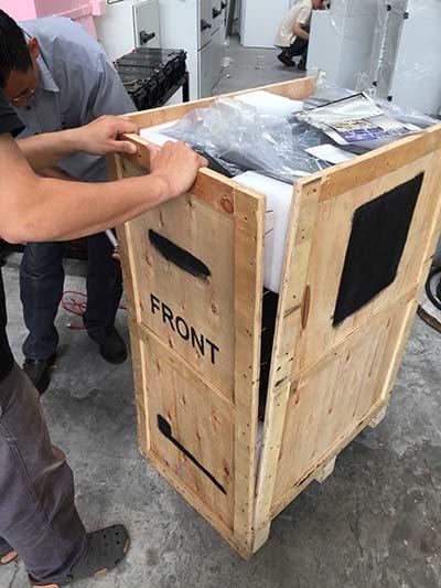 Two people opening a wooden crate labeled 