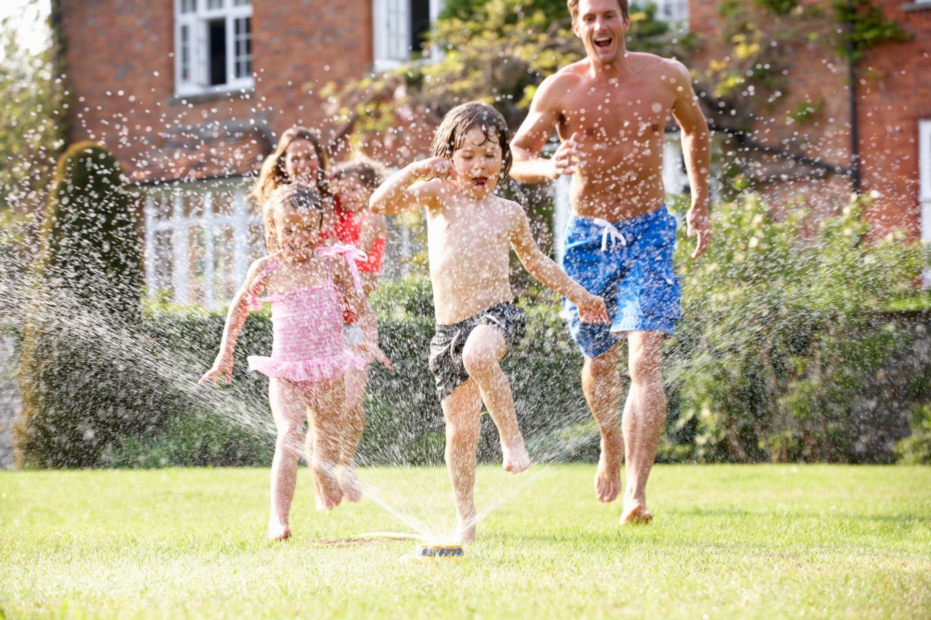 Family Playing at Water Sprinklers — Butler, NJ — Precision Sprinklers