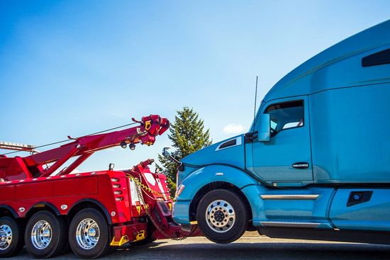 Red Tow Truck Towing Blue Truck — Haltom City, TX — AA Wrecker Service Truck Carrier with Mini Vans on Road — Haltom City, TX — AA Wrecker Service