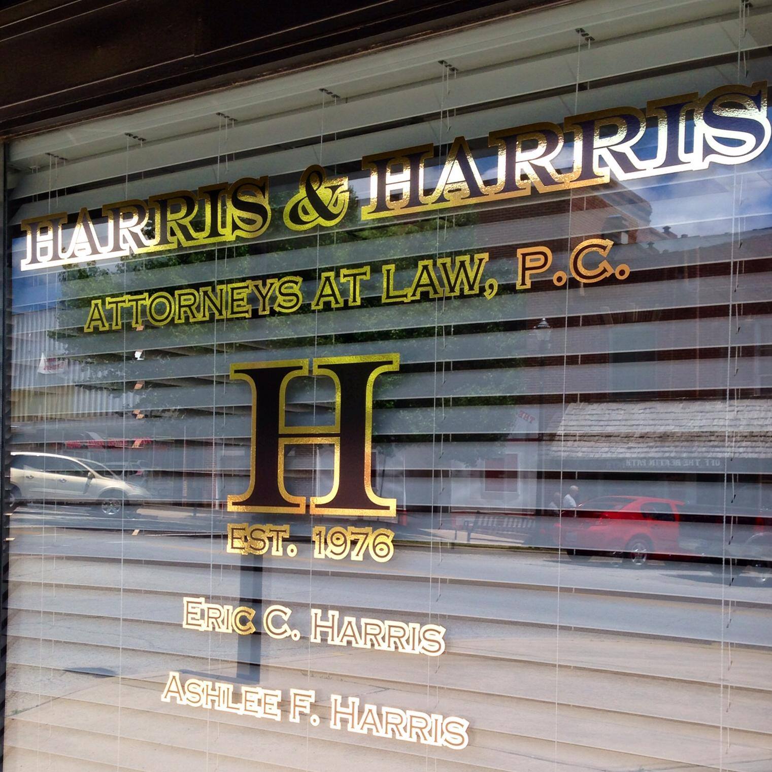 Storefront window sign for Harris & Harris Attorneys at Law, P.C., with gold lettering and initials on glass