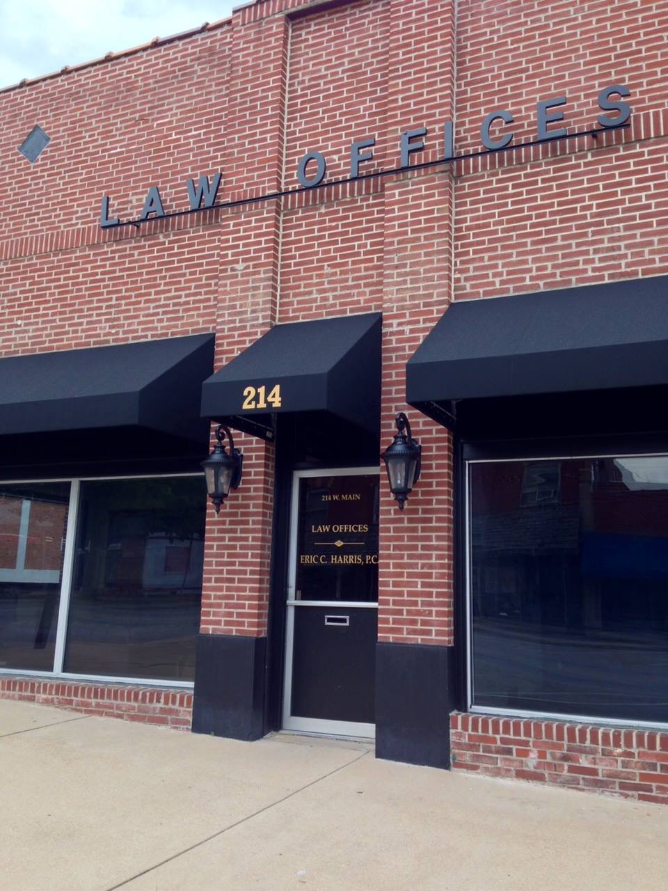Brick office storefront with black awnings, address 214, and a glass entrance door