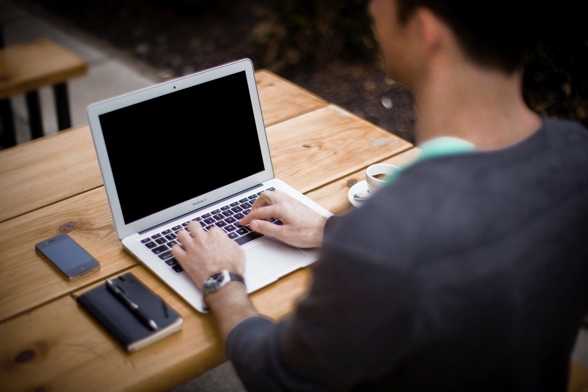 a man is typing on a laptop on a wooden table