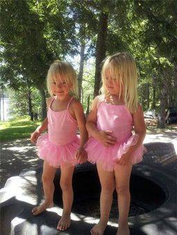 twin girls in pink dresses playing outside 