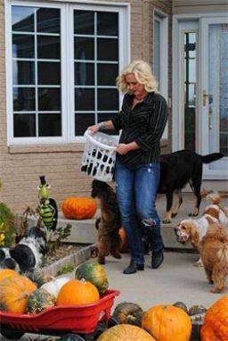 Woman carrying puppies in a laundry basket in front of her house