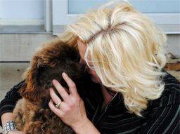 Kimberlee cuddling with her dog in front of her house