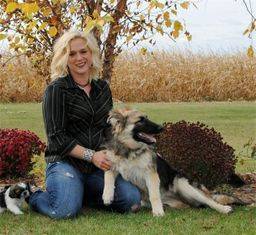 Woman posing with her dog in front of a tree