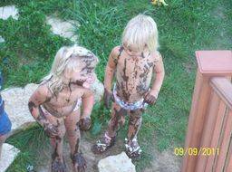 two young girls laughing after jumping in mud puddles