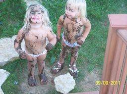 two young girls returning home after jumping in mud puddles 