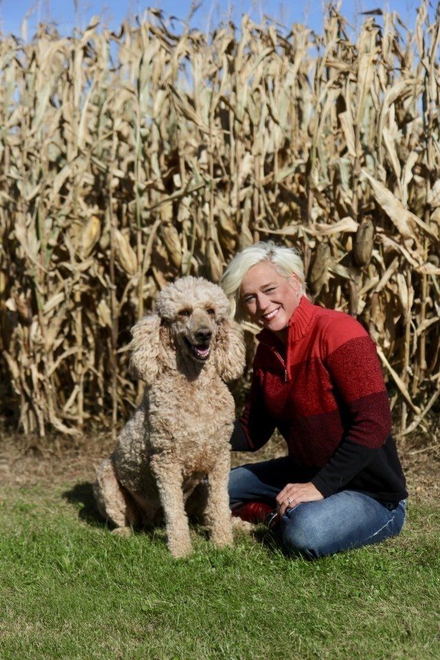 Kimberlee laying with a dog in front of a corn field