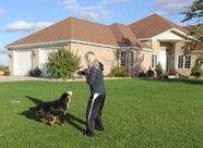 Woman playing with dog in front of her house
