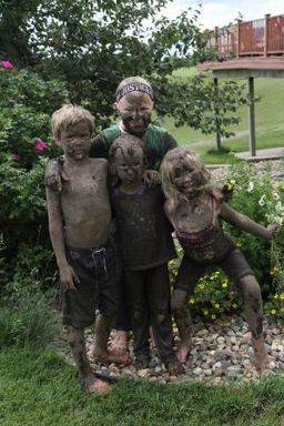 Group of children posing for a photo after playing in the mud