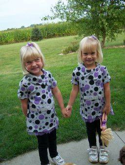 young twin girls with blonde hair in polka dot dresses outside