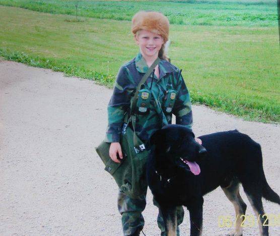 Kimberlee's oldest son in a camo outfit and a fur hat with a black lab
