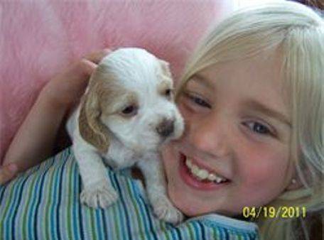 Kimberlee's daughter cuddling with a three week old puppy on a pink blanket