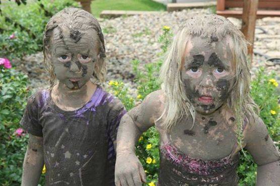 Kimberlee's twin daughters in their backyard after playing in the mud