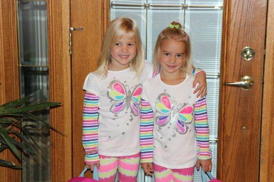 Kimberlee's twin daughters in matching outfits standing by their front door