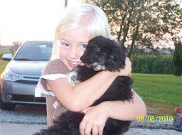 Kimberlee's daughter hugging a puppy in their driveway 