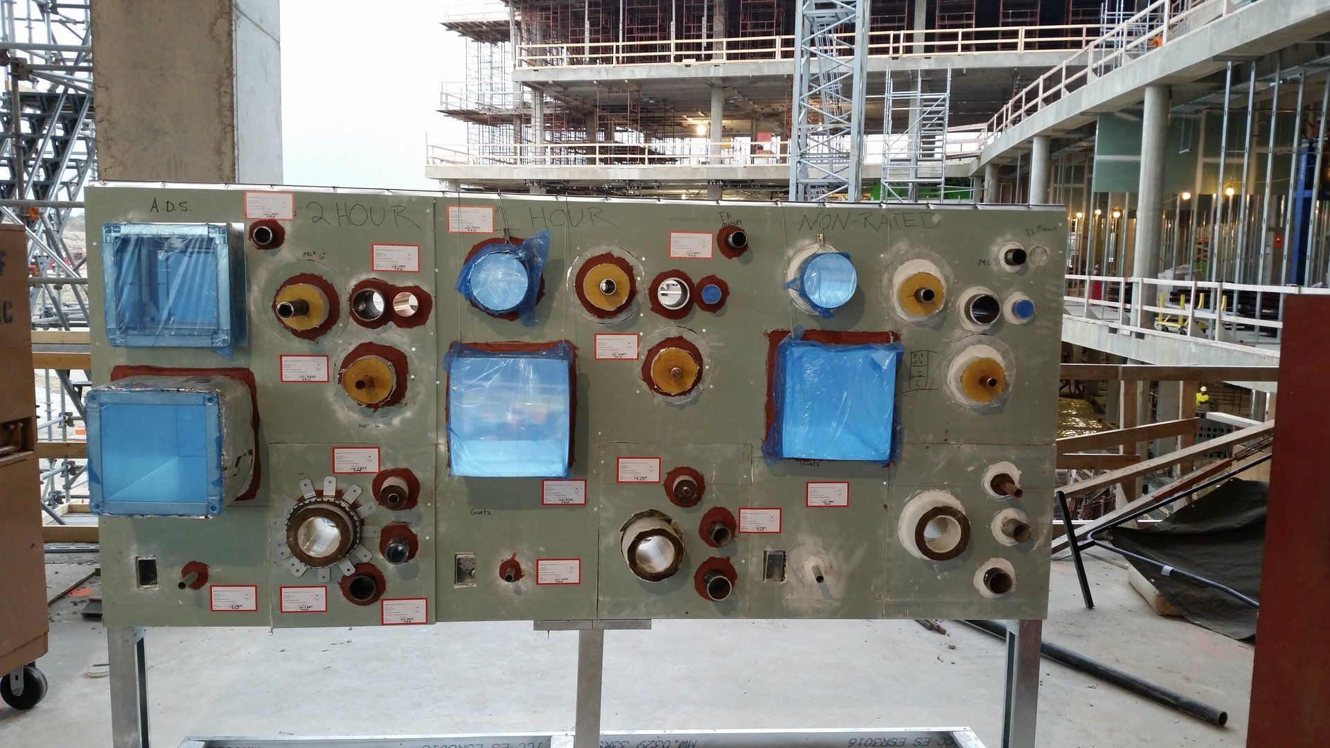 A large piece of equipment is sitting in front of a building under construction.