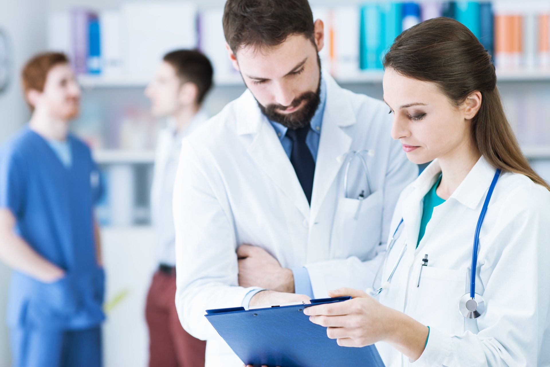 A man and a woman are looking at a clipboard in a hospital.