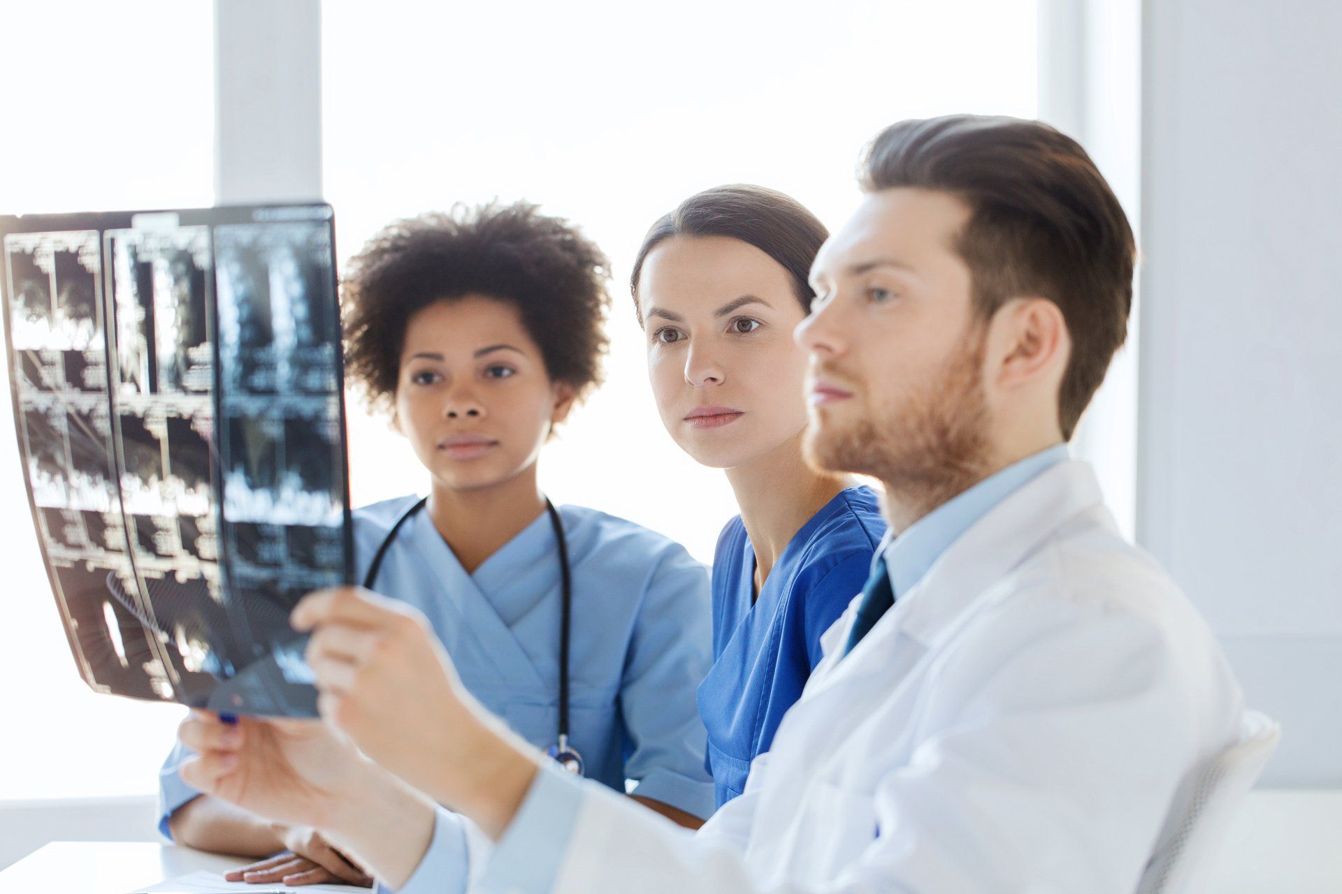 A group of doctors and nurses are looking at an x-ray.